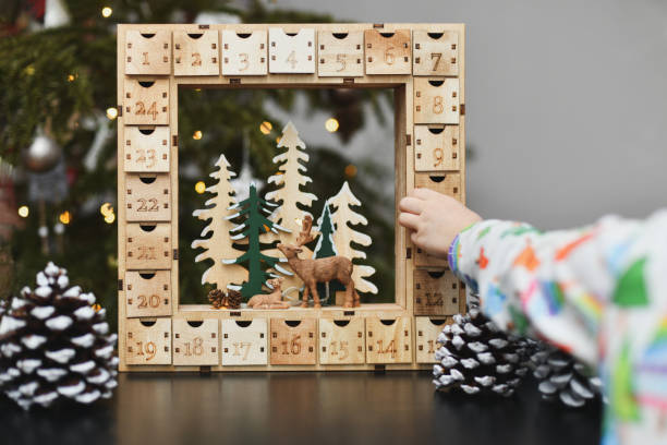 una niña abre el calendario de adviento de madera con regalos - advent calendar advent christmas childhood fotografías e imágenes de stock