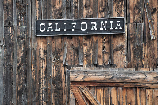 Old antique wood building exterior with door and old rusty hinges in ghost town in western USA. Useful as background.