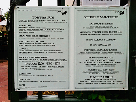 Horizontal closeup photo of the menu, printed with black text,  from a restaurant placed on a stand in the street outside the  venue. Denver, Colorado.