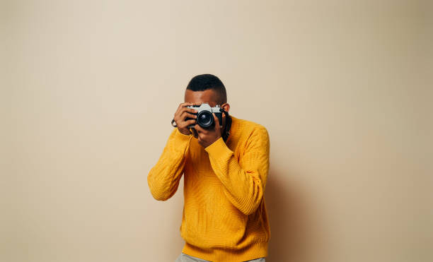 istock Unrecognizable man holding analog camera taking a photo over brown background. 1344353773