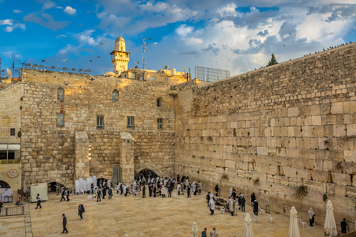 People stand at the Wailing Wall in the Old City, Jerusalem, Israel on a sunny day.