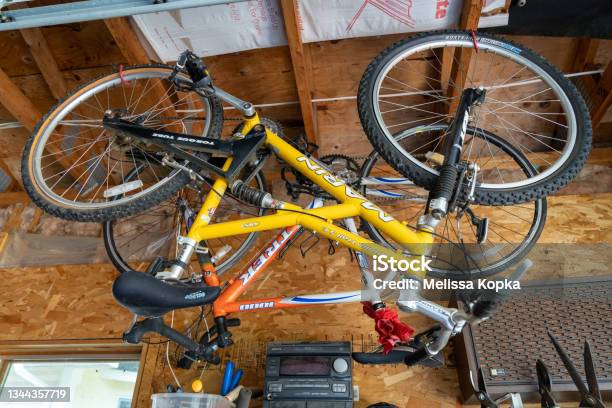 Two Bikes Hanging From The Ceiling In A Garage For Winter Storage Stock Photo - Download Image Now