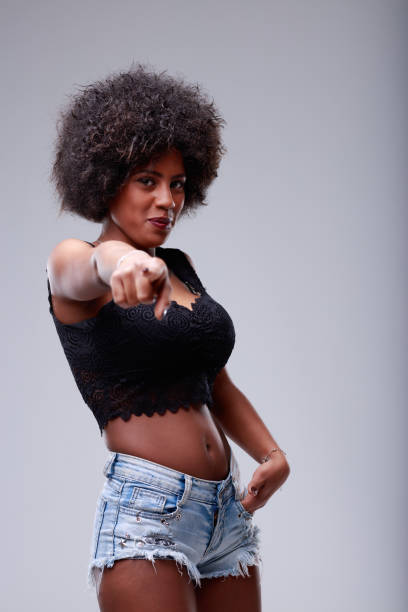 Cute amused young Black woman pointing down at the camera
