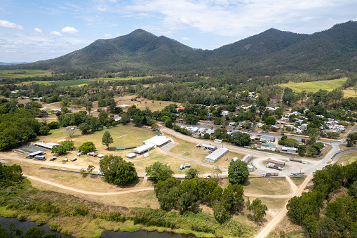 Aerial of small country town in a valley, showing semi trailers, showgrounds, cattle yards, homes, roads and lifestyle. Finch Hatton, Queensland, Australia