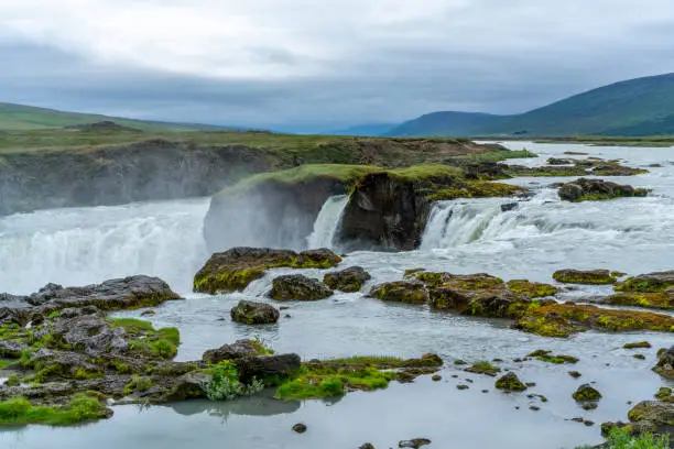 Top of Skjálfandafljót river right before  Godafoss Waterfall in Northern  Iceland. In background is surrounding mountain and cloudy sky.