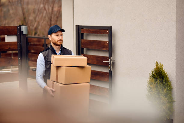 istock Delivery man carrying cardboard boxes to customer's home. 1344366556