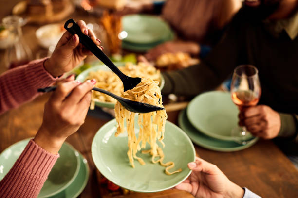 istock Close-up of people having pasta for lunch at dining table. 1344366722