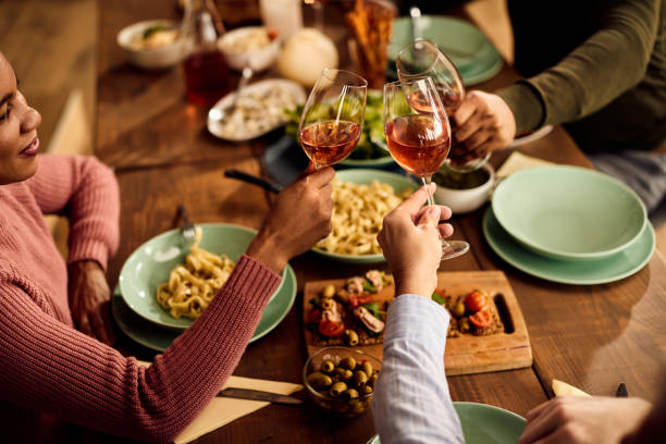 istock Close-up of multi-ethnic people toasting with wine while eating at dining table. 1344366724