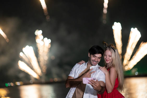 istock A young Caucasian couple enjoy taking their picture by using smartphone during celebration festival with firework. 1344369192