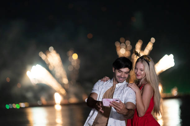 istock A young Caucasian couple enjoy taking their picture by using smartphone during celebration festival with firework. 1344369196