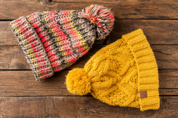 istock Colourful winter hats with pompons on wooden background. Top view 1344370295