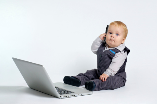Smart prodigy baby working with laptop and making calls