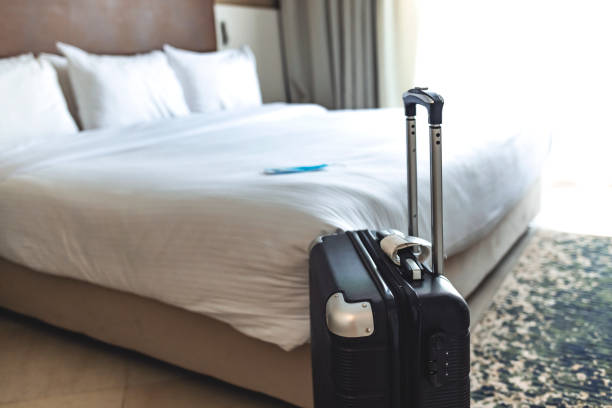 Close up of black luggage and surgical mask. Close up of black luggage and surgical mask. Hotel room bed background, copy space for text, Traveling in new normal lifestyle concept. Stay safe while travel during Covid 19 pandemic concept. hotel stock pictures, royalty-free photos & images