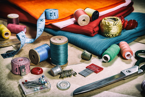 Creative image. Various accessories for needlework. A set of sewing accessories for sewing, spools of thread, fabrics, scissors and thimble close-up. Retro style