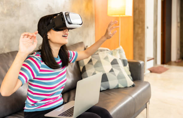 istock Young asian woman is using virtual reality headset. Neon light studio portrait. Concept of virtual reality, simulation, gaming and future technology.Asian woman play game in bedroom. 1344387781