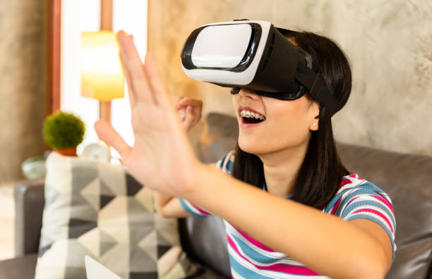 istock Young asian woman is using virtual reality headset. Neon light studio portrait. Concept of virtual reality, simulation, gaming and future technology.Asian woman play game in bedroom. 1344387818