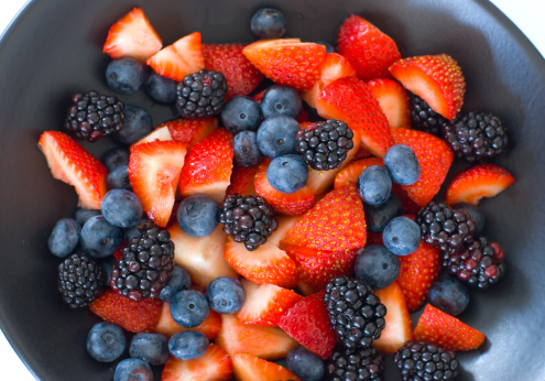 Fresh Fruit Bowl containing strawberries, blueberries and blackberries.  Fresh colorful vibrant fruit in bowl.  Looking down.  Studio light.