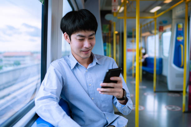 Male intern working on digital tablet in electric train Young Asian man use tablet application on his digital tablet for urgent work in electric train bts skytrain stock pictures, royalty-free photos & images