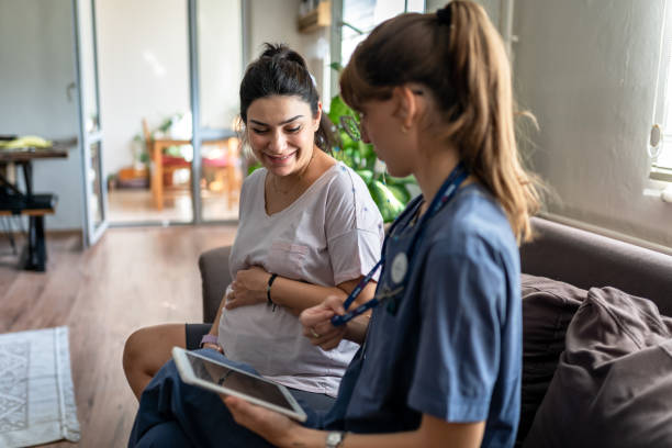 Home healthcare nurse visits pregnant woman at home stock photo