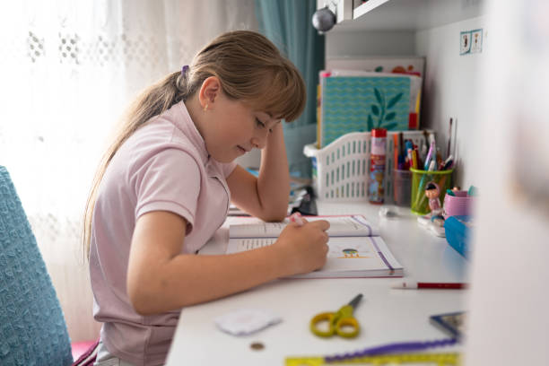 istock Little girl doing homework at home 1344405027
