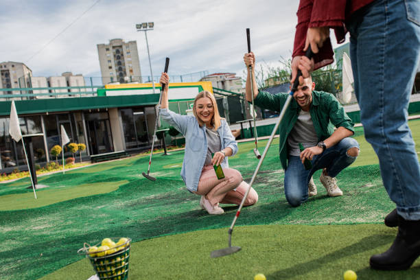 group of friends enjoying together playing mini golf in the city. - golf four people young adult playing imagens e fotografias de stock