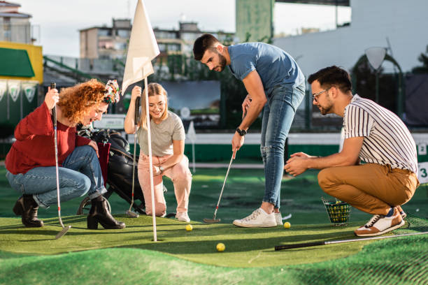 group of friends enjoying together playing mini golf in the city. - golf four people young adult playing imagens e fotografias de stock