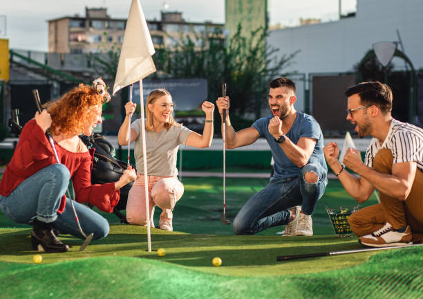 group of friends enjoying together playing mini golf in the city. - golf four people young adult playing imagens e fotografias de stock