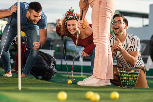 group of friends enjoying together playing mini golf in the city. - golf four people young adult playing imagens e fotografias de stock