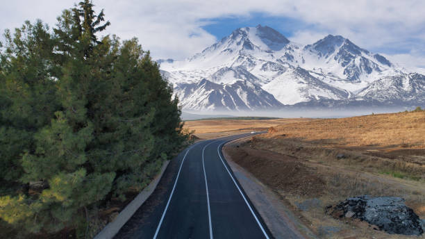 istock Scenic road with snowy mountains in background 1344410127
