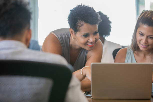 istock Manager assists employee at her desk in busy office 1344411491