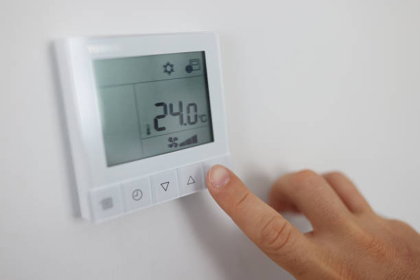 istock Person regulates air temperature in room through remote control on wall 1344412642