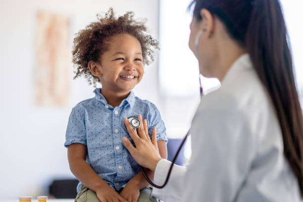 doctor listening to little boys heart - healthcare stockfoto's en -beelden