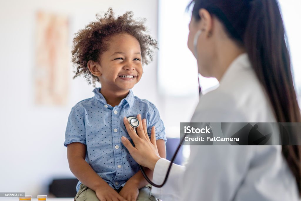 Doctor Listening to Little Boys Heart A female doctor of Asian decent listens to her patients heart with her stethoscope.  The little boy is sitting up on the exam table smiling back at his doctor as she holds the instrument to his chest. Doctor Stock Photo