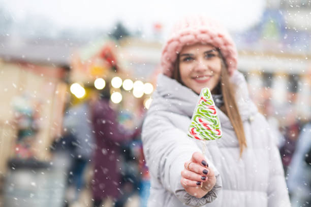istock Magnificent lady with candy on a christmas fair during the snowfall 1344413284