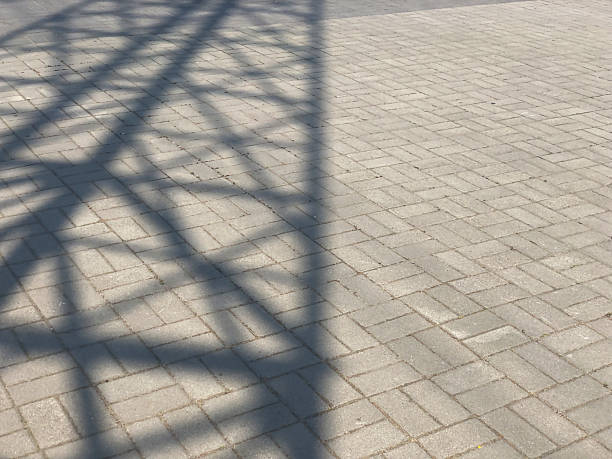 Stone pavement texture. Top view on cobblestoned pavement background. Abstract background of old cobblestone pavement street. Powerline shadow on a pavement