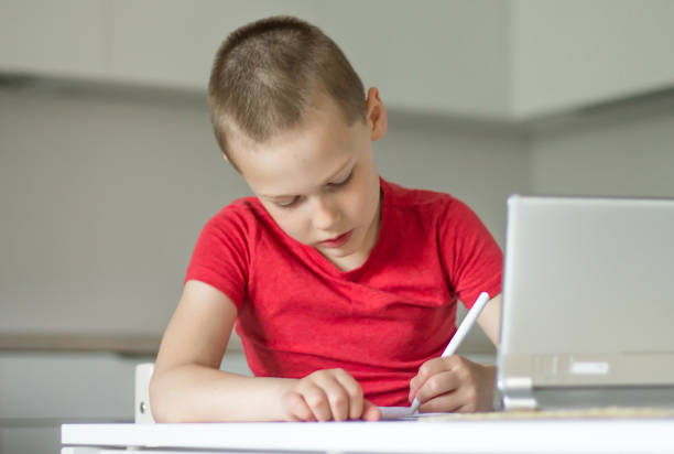 Boy 6-10 completes school lessons and homework online in the kitchen, looking at the tablet computer. The concept of distance education. Stay at home.