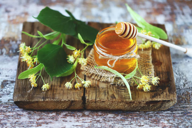 Linden honey in a jar. Leaves and flowers of linden. stock photo