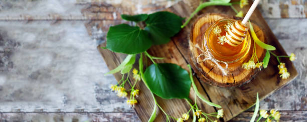 Honey stick, a jar of linden honey, linden flowers. stock photo