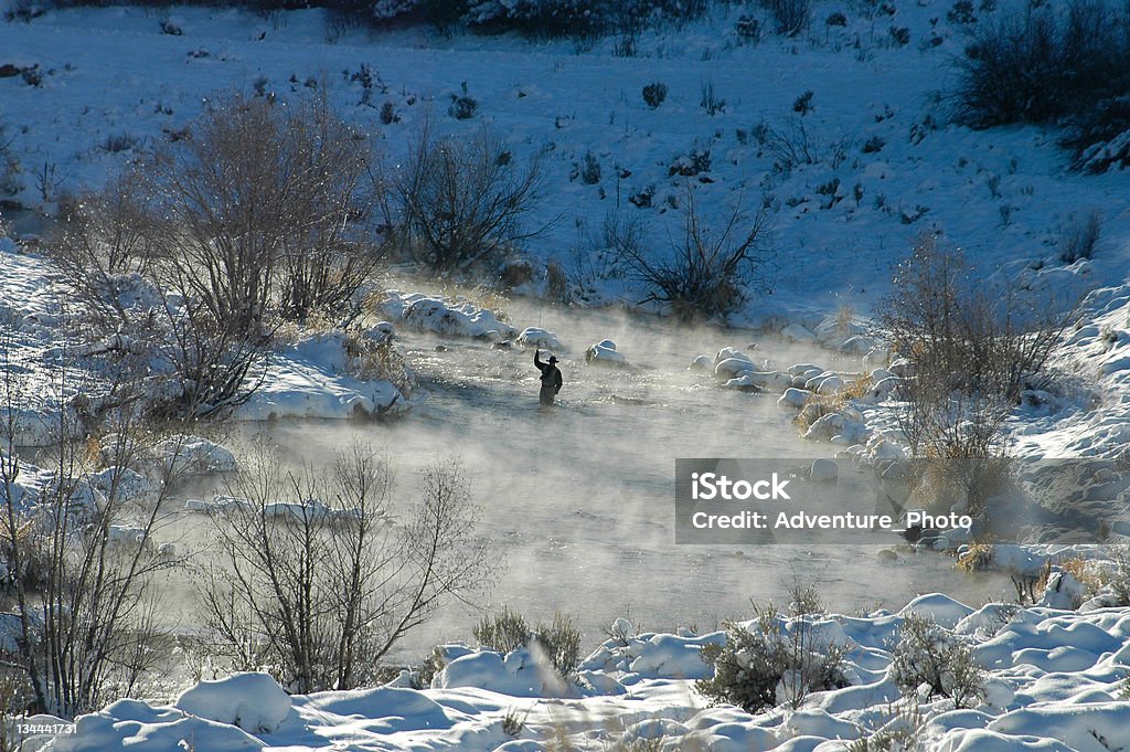 Homme pêche à la mouche et projetant en hiver avec vapeur montante - Photo de Activité de loisirs libre de droits