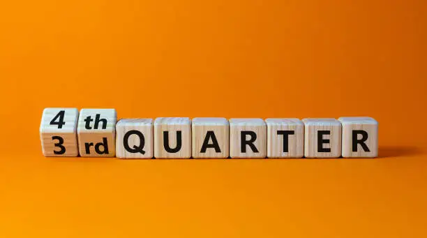 Photo of From 3rd to 4th quater symbol. Turned wooden cubes and changed words '3rd quater' to '4th quater'. Beautiful orange table, orange background. Business, happy 4th quater concept, copy space.
