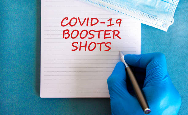 Covid-19 booster shots vaccine symbol. White note with words Covid-19 booster shots, beautiful blue background, doctor hand and metallic pen. Medical mask. Covid-19 booster shots vaccine concept. Covid-19 booster shots vaccine symbol. White note with words Covid-19 booster shots, beautiful blue background, doctor hand and metallic pen. Medical mask. Covid-19 booster shots vaccine concept. booster dose stock pictures, royalty-free photos & images