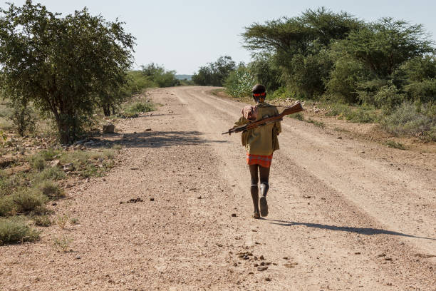 Hamer tribe man Omo Valley, Ethiopia - December 10, 2013: An unidentified man from the Hamer tribe with a gun walks along the road. hamer tribe photos stock pictures, royalty-free photos & images