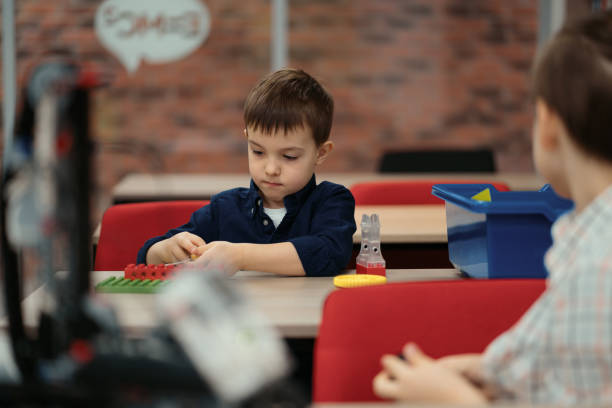 istock Two boys kids of different age playing with robot toy at school robotics class 1344422041