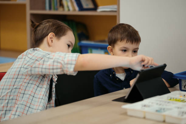 istock Two boys kids of different age playing with robot toy at school robotics class 1344422496