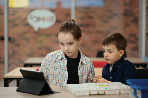 istock Two boys kids of different age playing with robot toy at school robotics class 1344422501