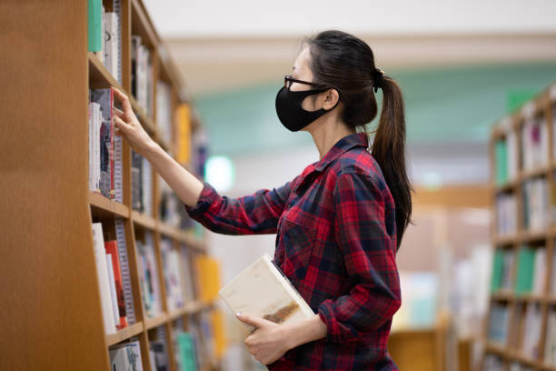 istock Woman reading a book wearing a mask 1344423214