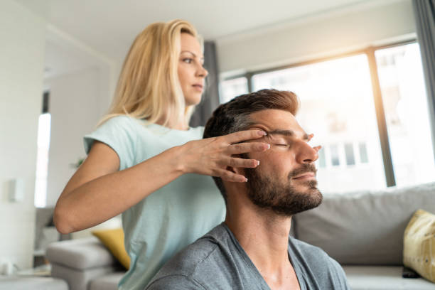 крупный план молодого человека, получающего расслабляющий массаж виска от жены. - head massage стоковые фото и изображения