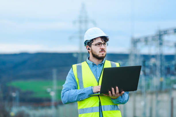 istock Electrical engineer working on a laptop in front of Electricity power station 1344425622