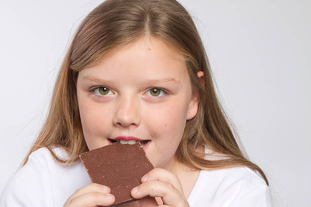 istock Young girl biting into a piece of chocolate 134442636