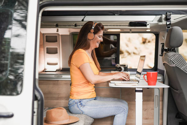 istock Mature woman working inside mini van camper with computer laptop wearing wireless headphone 1344428900